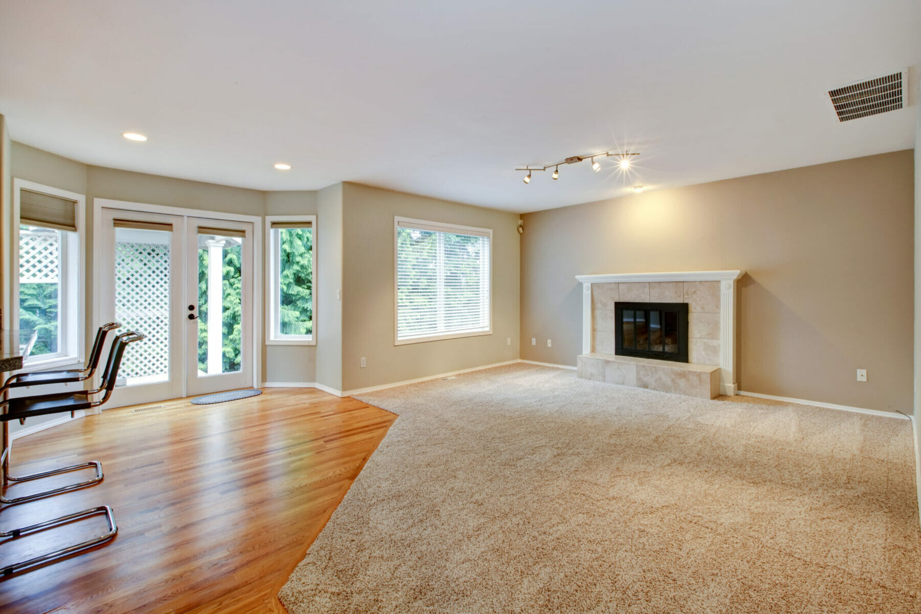 Large bright new living room with fireplace and beige carpet.